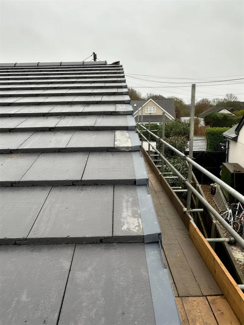 New grey tiled extension roof with a dry verge, seen from the scaffold
