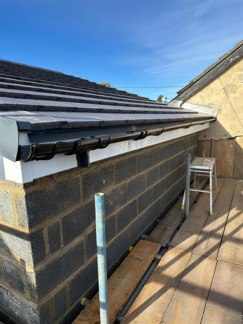 New tiled roof with white fascia and black gutters on an extension