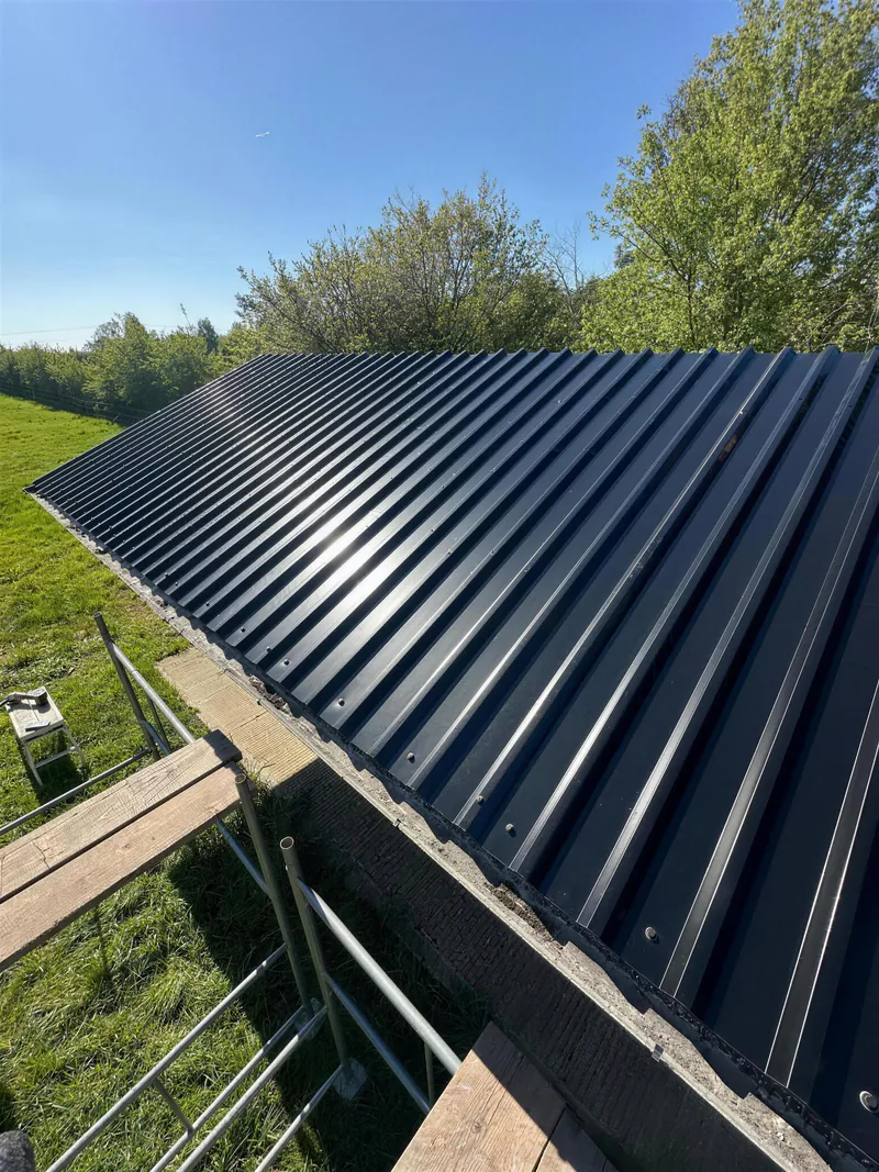 New black corrugated metal sheet roof on a long outbuilding