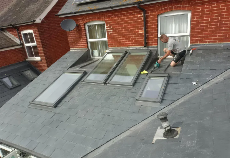 Roofer fitting roof windows into a new slate roof on a rear extension