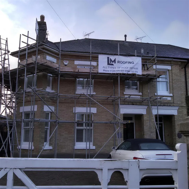 House under scaffolding with an LM Roofing sign on the front