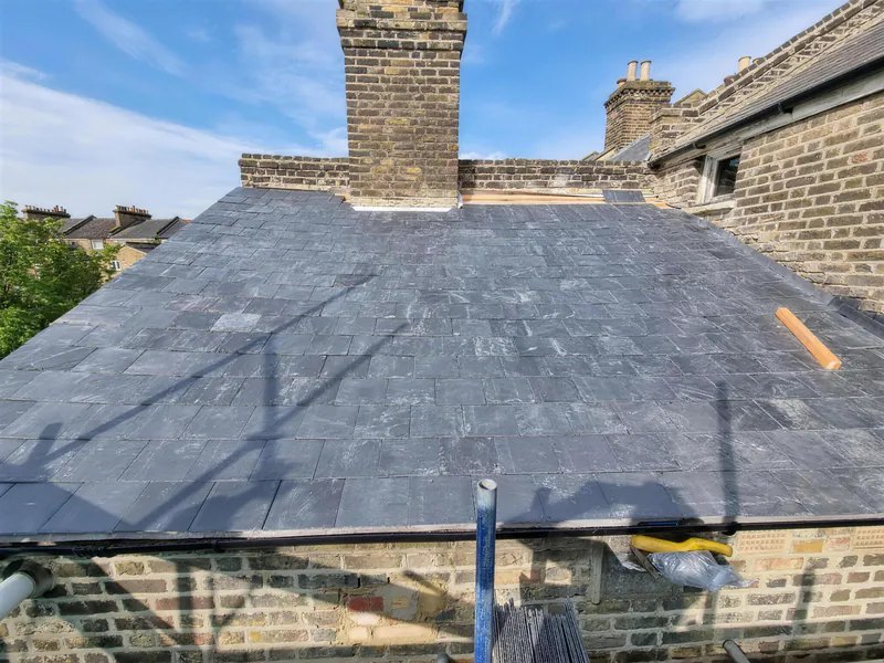 New natural slate roof on a terraced house with a brick chimney